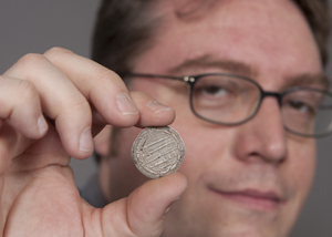 UC historian Robert Haug holds a late eighth-century coin from Baghdad. Medieval coins from Central Asia and the Middle East chronicle political, cultural and social shifts as Islam took root over several centuries. Photo by Dottie Stover, University of Cincinnati