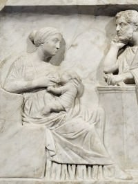 Mother breastfeeding a baby in the presence of the father. Detail from the sarcophagus of Marcus Cornelius Statius, who died as a young child. Marble, Roman artwork, ca. 150 AD.  Photo by Marie-Lan Nguyen 